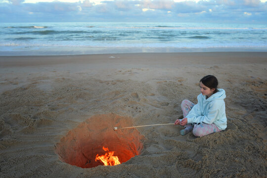 Side view tween girl roasting marshmallow beach camp fire Outer