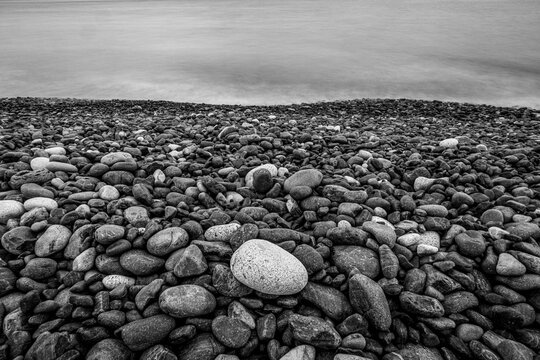 Black & white photo of pebbles on a rocky beach along the Maine coast.