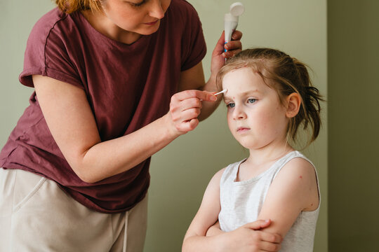 Young child with chickenpox receiving care from mother at home