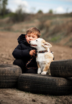 Little boy tenderly hugging his Corgi puppy outdoors.
