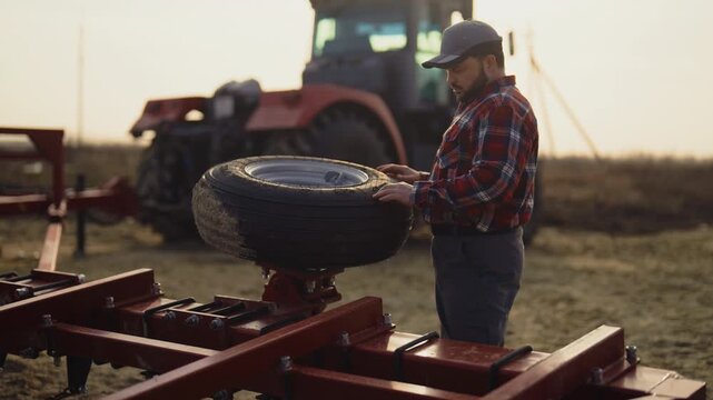 Agricultural machinery technician repairing wheel portrait in farmland in summer . Farming and agriculture, farmer working alone in field, Service and repair of equipment for harvesting and soiling