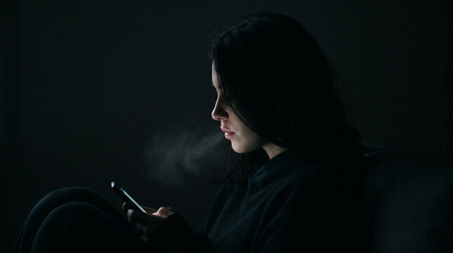 S&uuml;chtig nach KI. Einsame Frau s&uuml;chtig nach KI-Chatbot in der Dunkelheit. Sucht nach KI neues Problem in der Gesellschaft. Smombie 