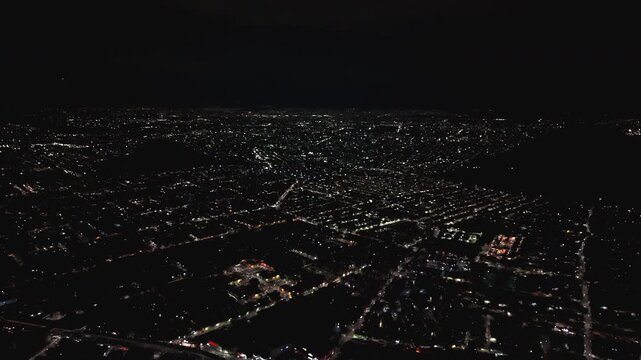 Aerial night view of a vast city urban grid with glowing street lights, 4K D-Log.