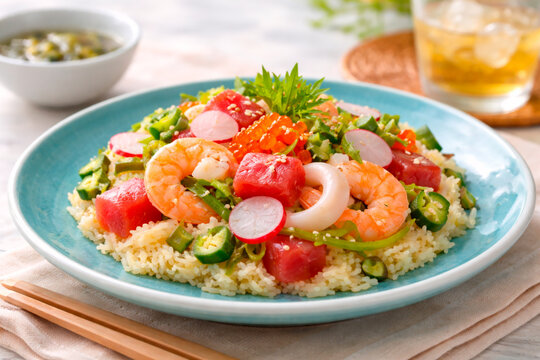 Okinawan-style chirashi sushi bowl with fresh tuna cubes, boiled shrimp, salmon roe, and okra served on a turquoise plate.
