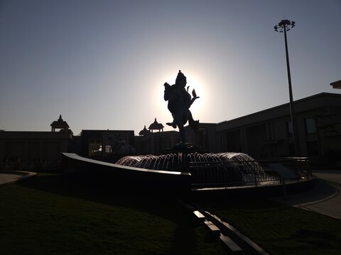 Silhouette view of the rotating Ardhanarishvara statue at Char Dham Temple in Vrindavan, India during sunset. Ardhanarishvara, the divine composite form of Lord Shiva and Goddess Parvati.