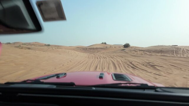 Driving a modern SUV through the endless sand dunes of the Middle East, POV shot of a desert road trip at dusk.