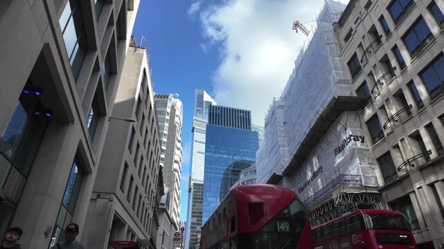 Iconic red double-decker bus driving through a busy street in london's financial district, showcasing the city's modern architecture and bustling business economy