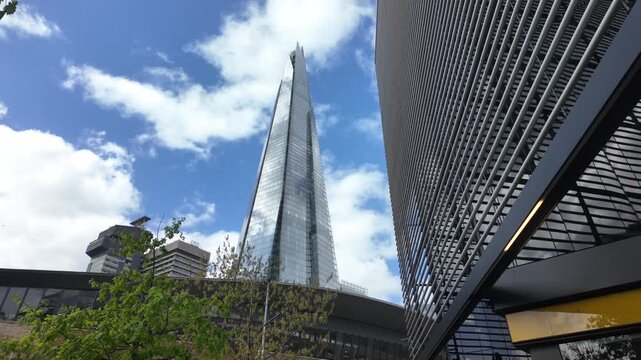 The shard skyscraper, an iconic london landmark, rising into a blue sky with clouds in the financial district, showcasing modern architecture and economic power