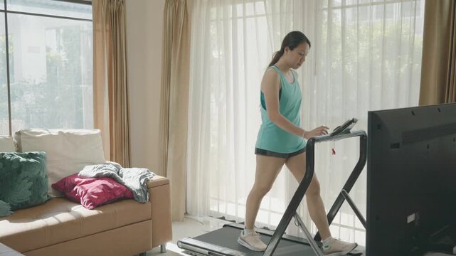 A person exercising on a treadmill at home, surrounded by natural light and comfortable furnishings.