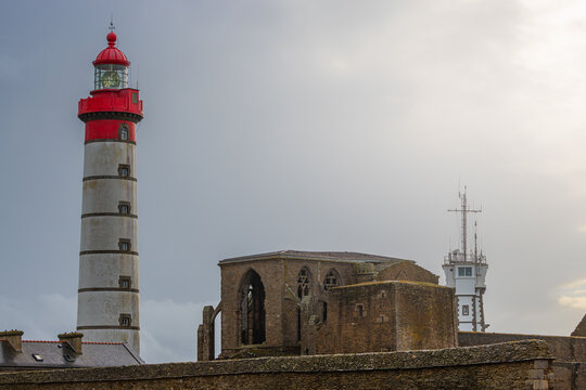 View of the Pointe Saint-Mathieu featuring the historic Saint-Mathieu Lighthouse and the ruins of the ancient abbey under a cloudy sky in Plougonvelin, Brittany, France.