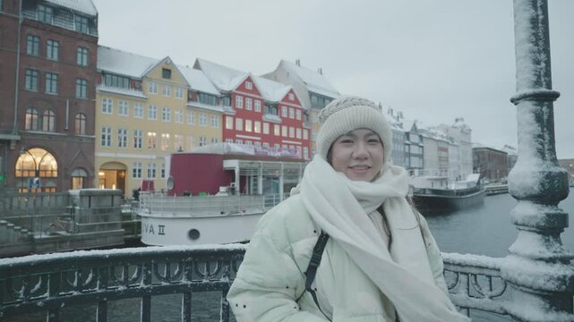 A picturesque winter scene featuring vibrant buildings lining a canal, blanketed in snow. The serene atmosphere captures the essence of a chilly day, perfect for leisurely exploration and enjoying sce