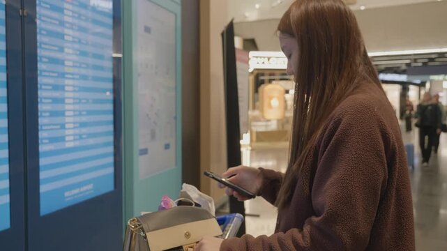 A person interacts with an information display in a contemporary shopping area, assisting their navigation.