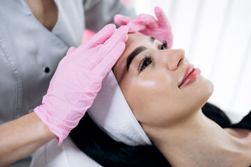 Naklejka premium Woman receiving a professional facial massage, rejuvenating her skin in a spa environment for beauty and wellness