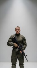 Fototapeta premium Military personnel holding rifle in green uniform standing isolated on gray background