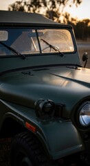 Fototapeta premium Vintage military jeep in golden hour sunlight with soft reflections on windshield