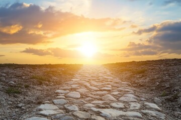 Obraz premium Pathway to success shows stone road leading toward the bright sun in the horizon under cloudy sky
