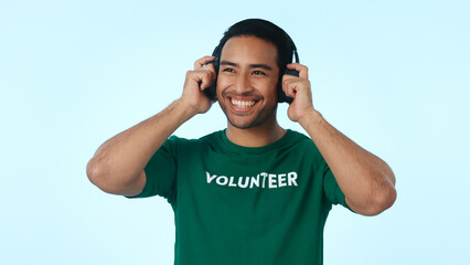 Fototapeta premium Volunteer, thinking and happy man with headphones, music and planning of charity project with audio. Blue background, reflection or person with social responsibility, radio and mockup space in studio