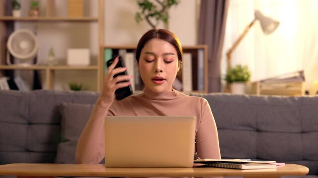 Young woman laptop home office remote work in living room sofa, smartphone communication multitasking, focused online learning and business workspace at desk with notebook, modern interior