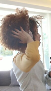 Vertical video: Tapping phone, denim friend cueing woman with headphones singing and moving at home