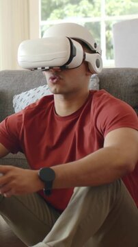 Vertical video: Reacting to VR app starting, man in red tee steering with white controller on couch