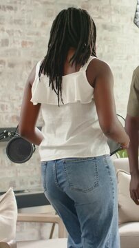 Tuning mic, tech stepping back as host in white-top moving to studio chair, sitting reading tablet