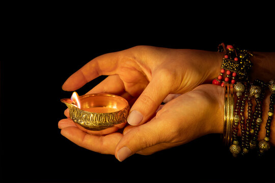 Hands with Diwali lamp diya or Deepavali or Deepawali. Hindu festival of lights. Celebrating in Indian religions Jainism and Sikhism. Offering to the gods, a spiritual rite. Close up view, out of focu