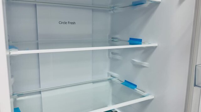 Empty refrigerator interior with glass shelves, bright LED lighting illuminating three tempered glass shelves and removable.