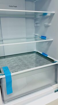 Empty refrigerator interior with glass shelves, bright LED lighting illuminating three tempered glass shelves and removable.