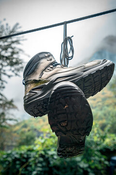 Worn hiking boots hanging representing concepts like the end of a journey, accomplishment, retirement, and a well-traveled life.