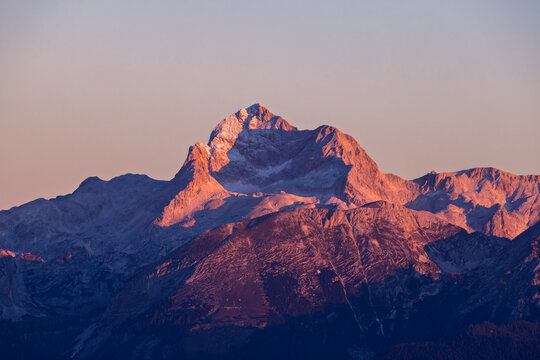 View of the majestic Mount Triglav peak glowing with warm alpenglow during sunset in the Julian Alps Sorica, Skofja Loka, Slovenia.