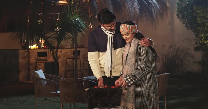 Indian young adult gen z male female girl couple give high five cook party food on barbecue house place. Happy man woman talk speak share gossip spend time enjoy picnic trip night cold have fun joy