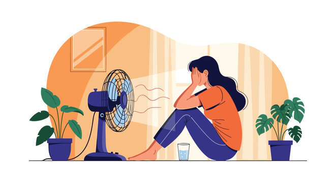 Young woman sitting on the floor in her living room trying to cool down with a fan during a summer heatwave day.