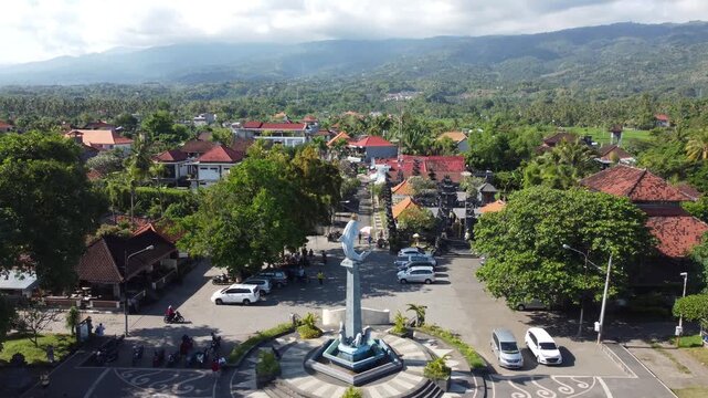 Cinematic aerial drone lifting off from the dolphin statue and pulling out to reveal the wider coastal landscape of Lovina, North Bali, Indonesia.