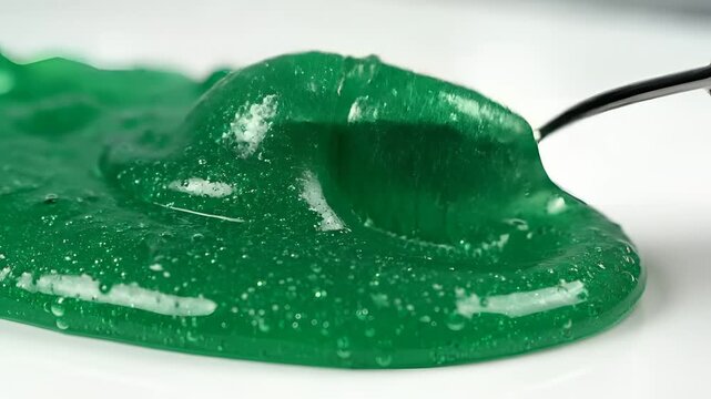 Closeup of green slime being scooped with a metal spoon.