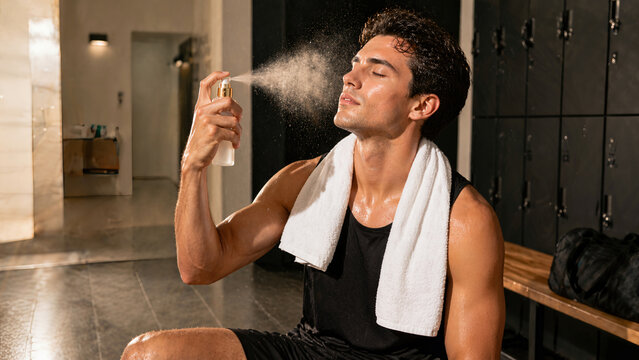 Young Athletic Man Refreshing with Facial Mist Spray in Gym Locker Room After Intense Workout
