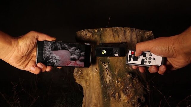 Wireless infrared camera streaming night footage to a smartphone in a backyard. Remote control zoom highlights surveillance, security monitoring, wildlife tracking, smart outdoor protection use cases.