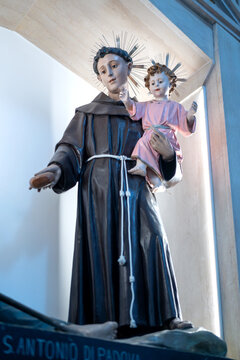 Religious statue of Saint Anthony of Padua holding the Child Jesus inside a Catholic church in Alberobello, Puglia, Italy. Sacred Christian sculpture with halos, soft natural light
