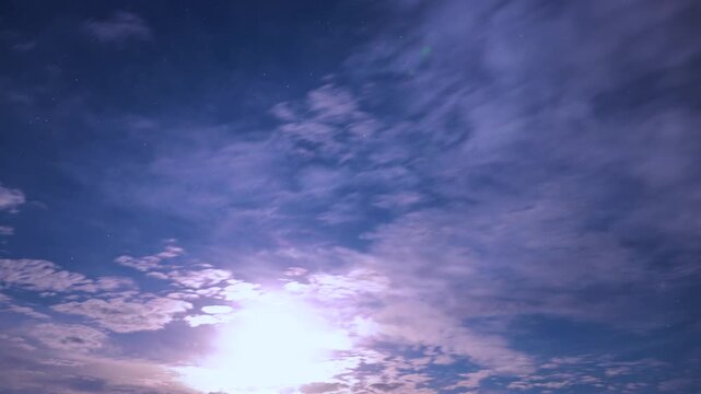 Bright full moon illuminating textured altocumulus clouds at night, timelapse