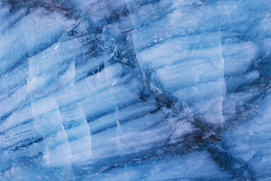 View of the deep blue ice textures and crevasses of the Svinafellsjokull glacier with dark volcanic ash streaks Sveitarfelagid Hornafjordur, Iceland.