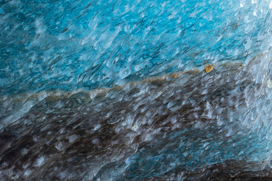 View of the textured blue ice and dark volcanic sediment layers of the Svinafellsjokull glacier in Sveitarfelagid Hornafjordur, Iceland.