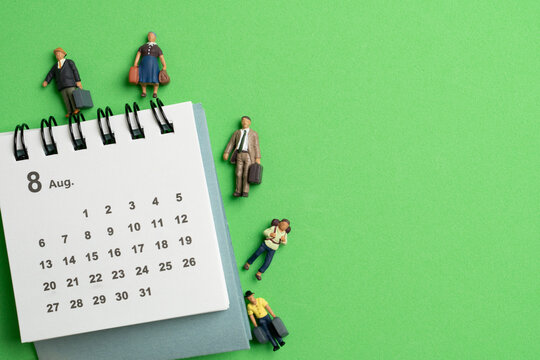 close up of calendar and miniature figures on the green table background, planning for business meeting or travel planning concept