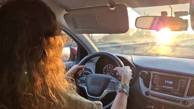 Woman driving highway, golden sunset light illuminating long hair, view from passenger seat showing travel journey