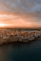 Fototapeta premium Aerial view of Antibes, France at sunset shows ramparts, stone towers, terracotta rooftops, marina, and the Chateau Grimaldi Musee Picasso by the Mediterranean.