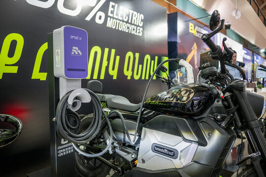 Silver electric motorcycle charges at modern Enel X Way charging station