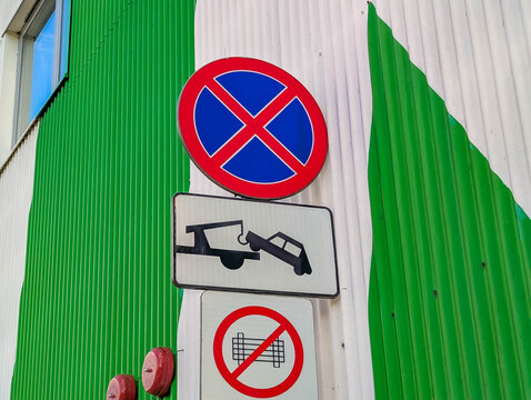 Warsaw, Poland, March 01, 2026. No parking and tow away zone road signs on a green corrugated metal wall in Warsaw. High quality photograph.