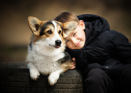 Heartwarming portrait of a young boy and his Corgi puppy together.