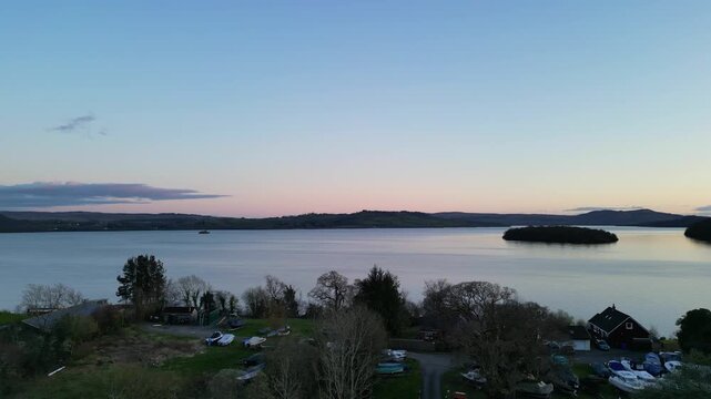 Aerial View of Calm Water of Massive Lake at Balmaha Valley Village Near Glasgow Landscape During Sunset. Village is a popular tourist destination for picnickers and day trippers from Glasgow