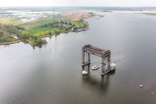 High aerial view of Hubbrucke Karnin over the Peenestrom near Karnin, Usedom, Mecklenburg-Vorpommern, Germany, with surrounding water, village edge and green fields.