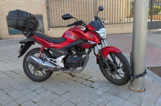 Vista lateral de moto Honda CB 125 F con portaequipajes estacionada en Madrid, Espa&ntilde;a, 19 de marzo de 2026