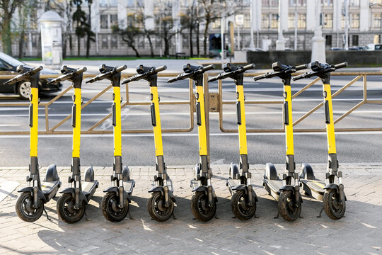 Electric scooters parked in a row on urban sidewalk, sustainable transport concept.